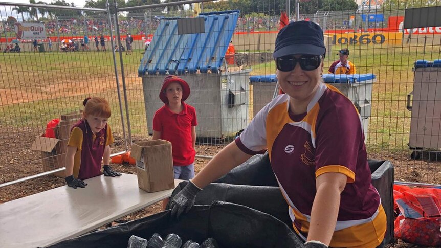 School students and a parent wearing gloves at the Townsville 400 beside a large bale of plastic bottles.