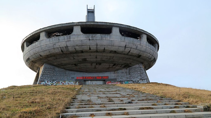 a spaceship shaped building  on a hill with the sky as a backdrop