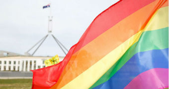 A rainbow flag is waved in front of Parliament House in Canberra.