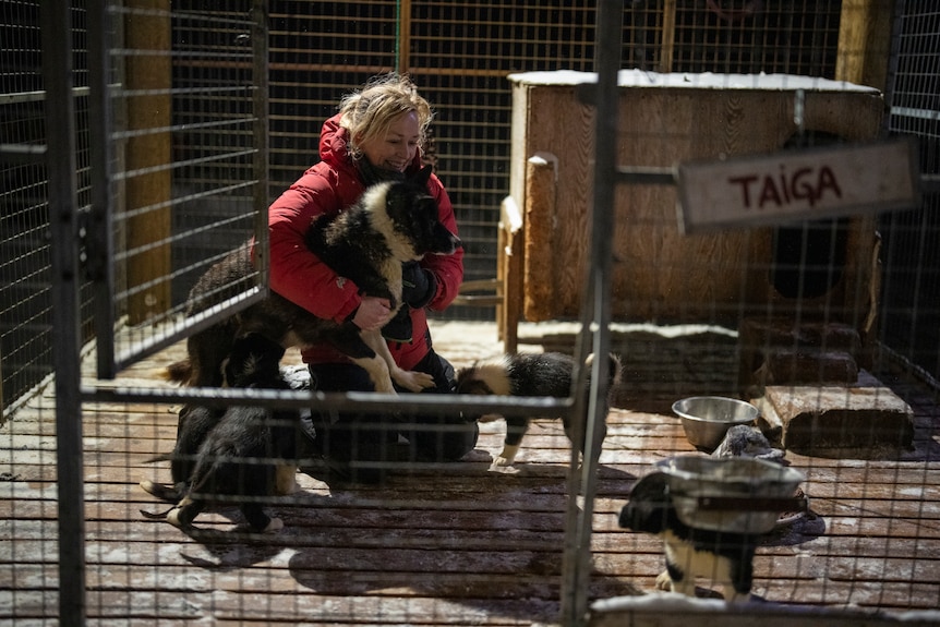 A woman in a red jacket hugs a dog 