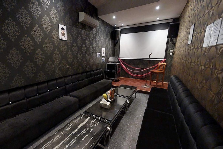 Inside a karaoke bar with black suede couches.
