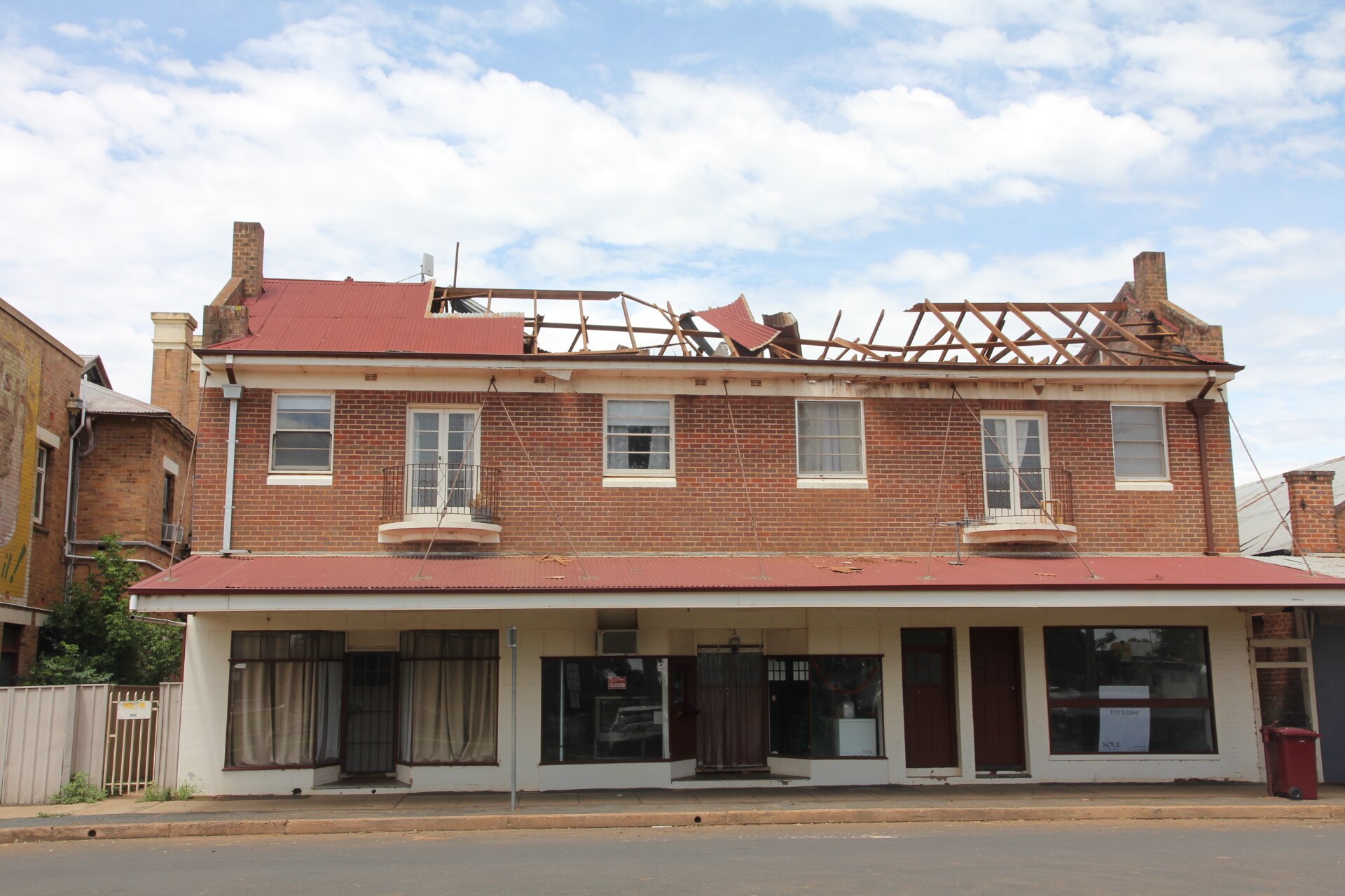Un gran edificio comercial de ladrillo rojo con el techo dañado y volado