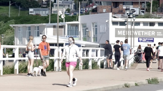 People walking around with masks at the Merewether surf house.