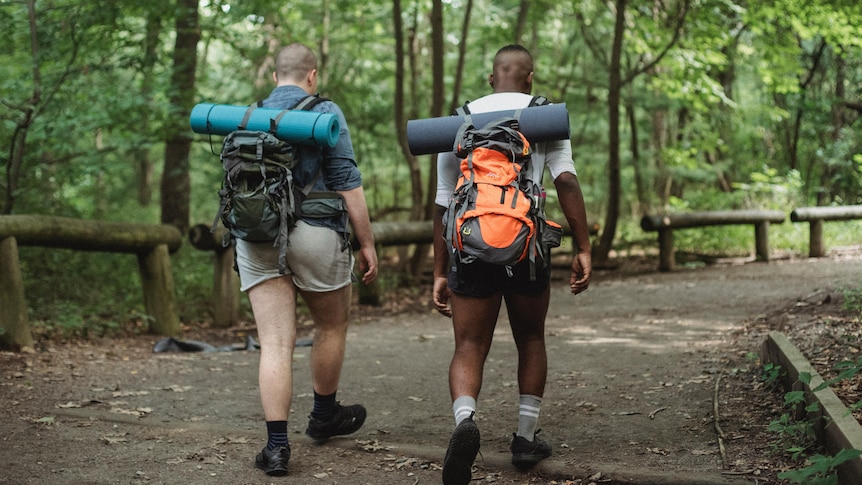 Two men walking with backpacks on in a nature setting