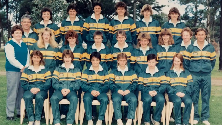 A soccer team wearing green and yellow uniforms poses for a group photo
