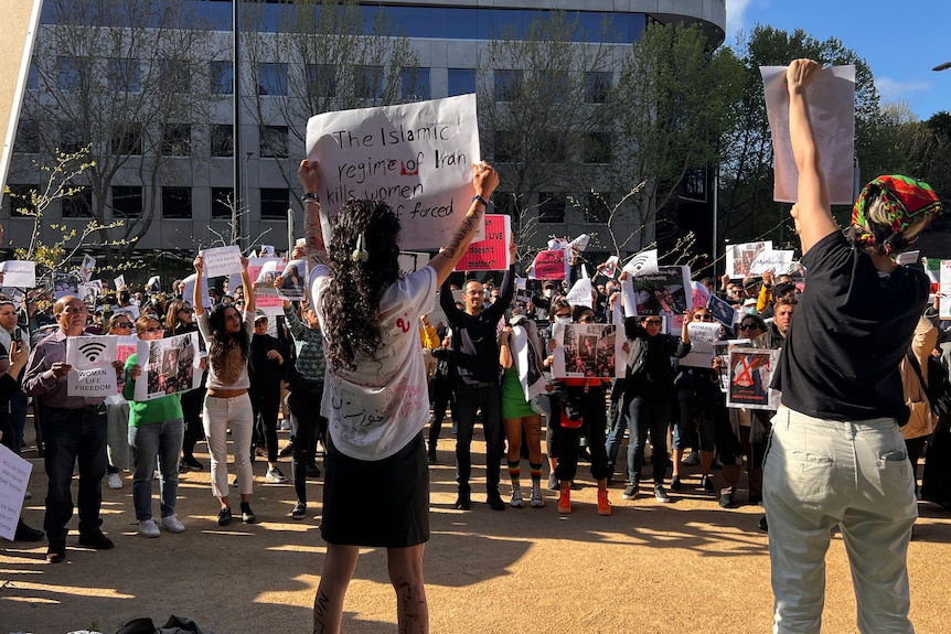 Protesters gather, holding placards reading 'They kill us in your silence' and other messages in support of women's rights.