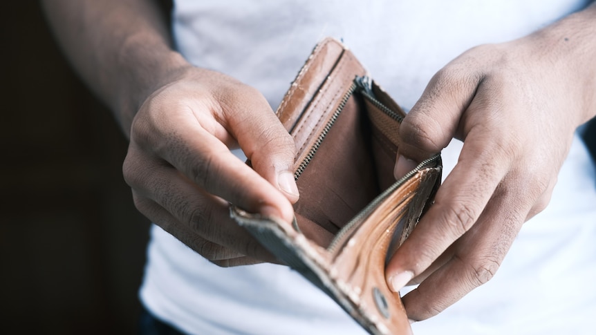 A man holds open an empty wallet.