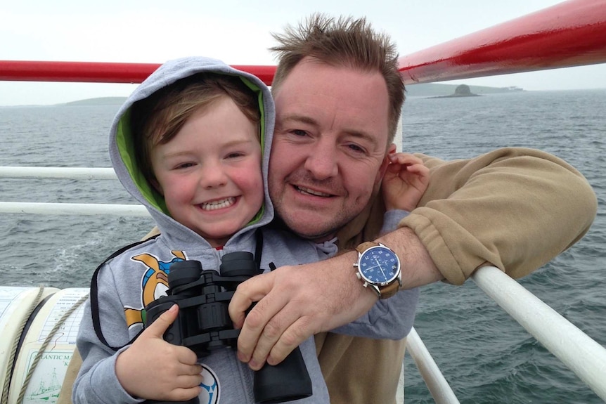 Lee Moran and his son Brodie Moran photographed together on a boat with water in the background.