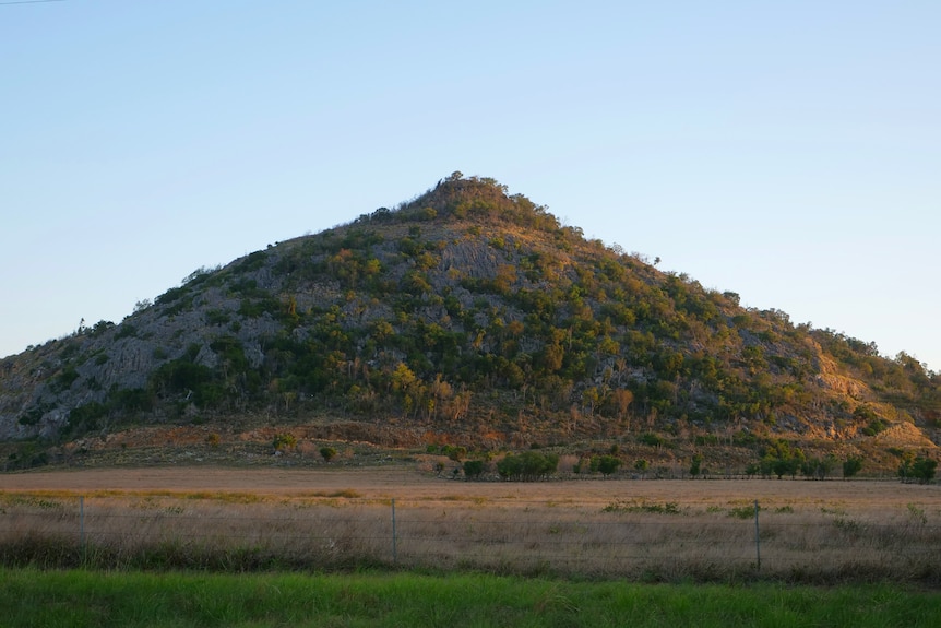 A small mountain in the distance at sunset.