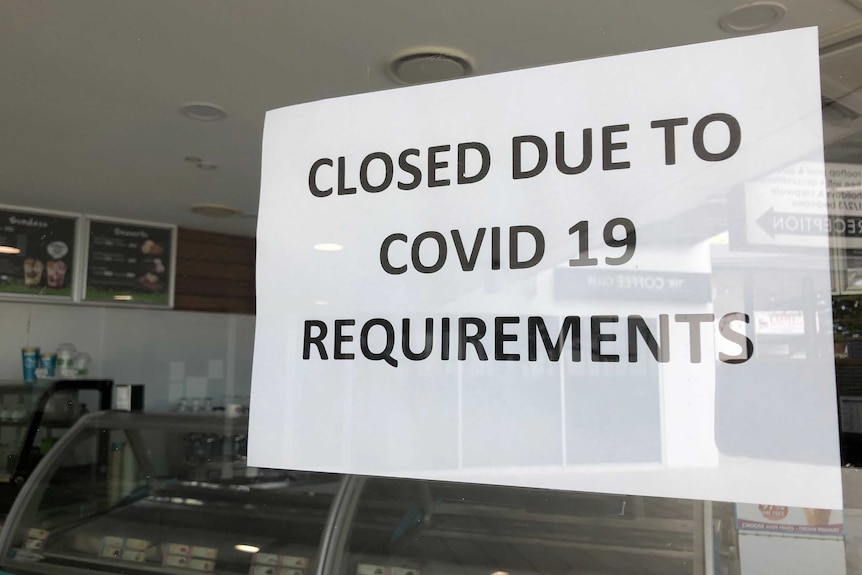 A sign reads closed due to COVID-19 requirements on a shop door.