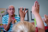 Kindergarten students raise hands to answer question