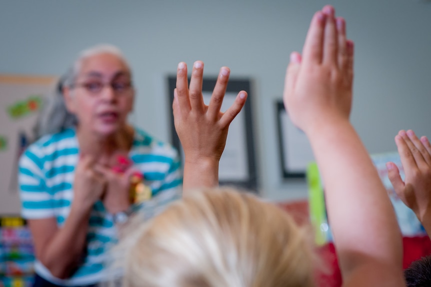 Kindergarten students raise hands to answer question