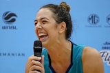 Southside Flyers WNBL player Jenna O'Hea laughs while holding a microphone.