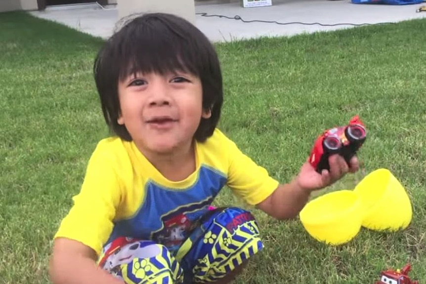 Ryan sits in his backyard and reviews a toy car.