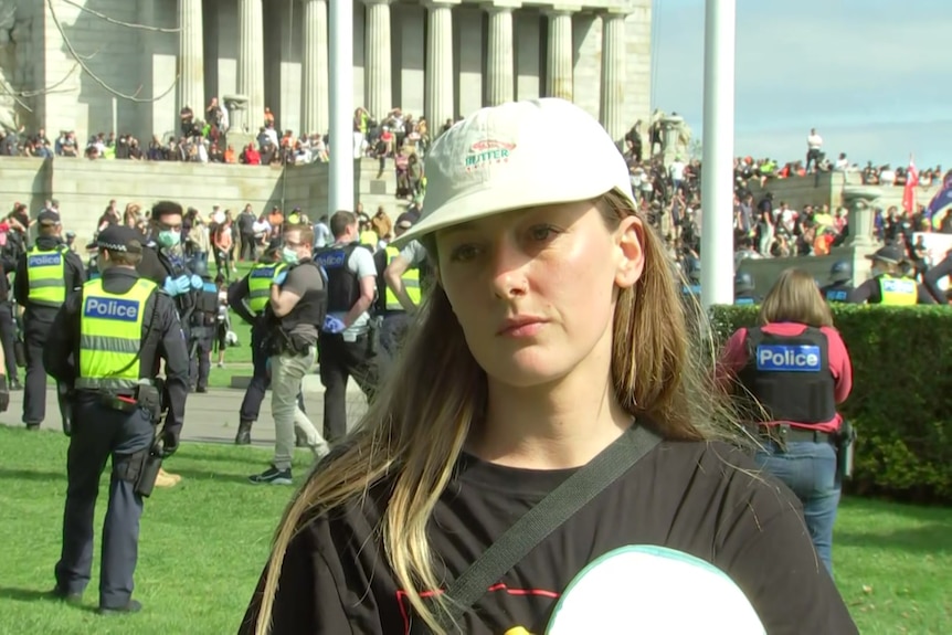 A woman in front of a protest at a war memorial