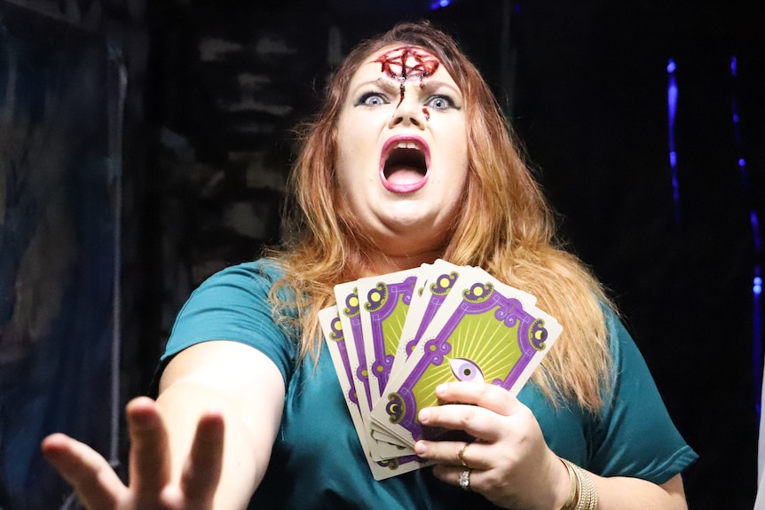 An actor dress in a Halloween costume as a tarot card reader, with a shocked expression