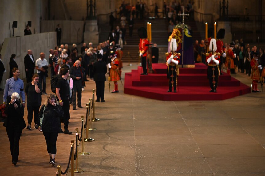 Members of the public pay their respects as they pass the coffin of Queen Elizabeth II in a dimly lit church hall