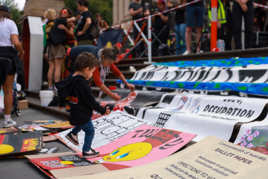 A child stands near some posters at Melbourne's Invasion Day rally on January 26, 2024.