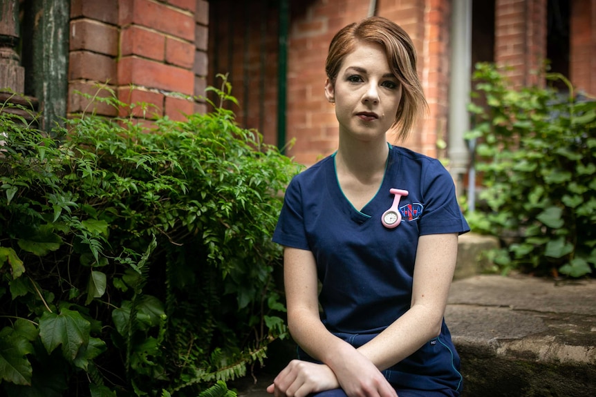 a person in scrubs sitting on the steps in front of the house