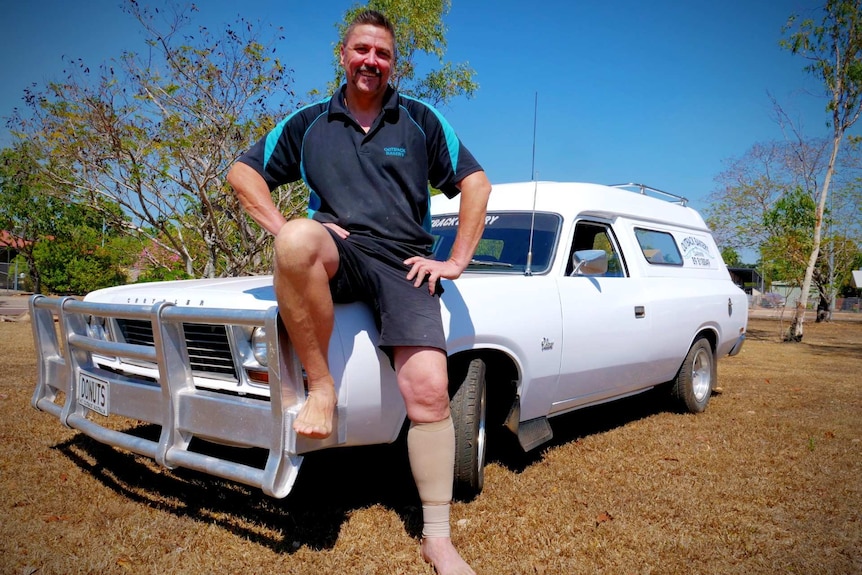 Man sits on the bonnet of a classic panel van.