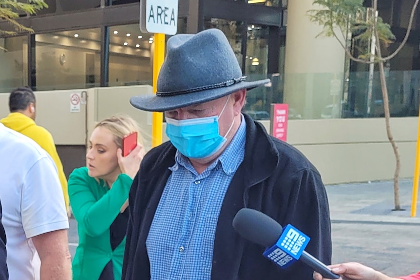 Douglas William McCarthy leaves court wearing a COVID mask.