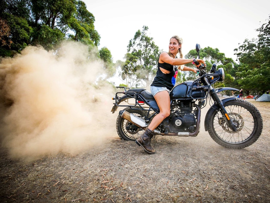 Woman on motorbike with a big cloud of dust behind