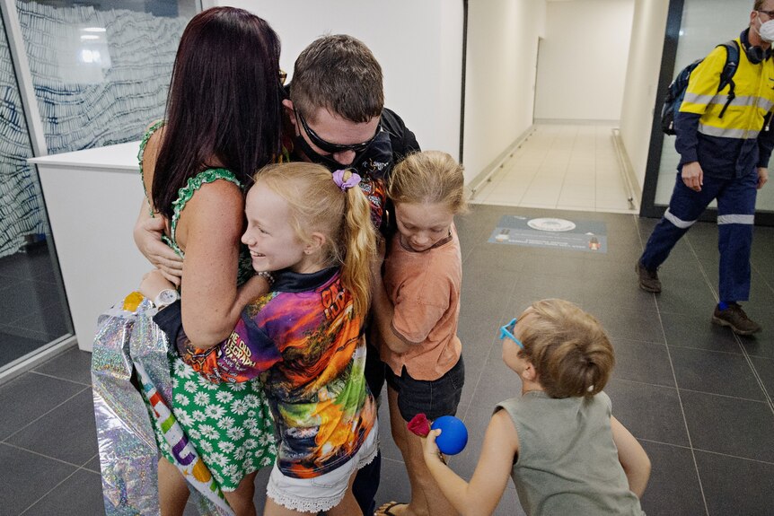 A family embraces a man in the terminal of the Darwin Airport.