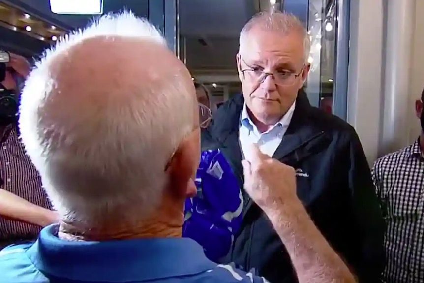 A still from grainy video footage shows a man, seen from behind, pointing at Scott Morrison