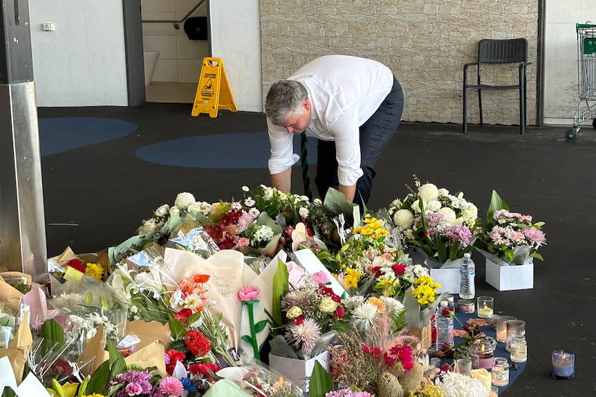 police minister mark ryan places flowers on a growing pile of floral tributes for a murder victim