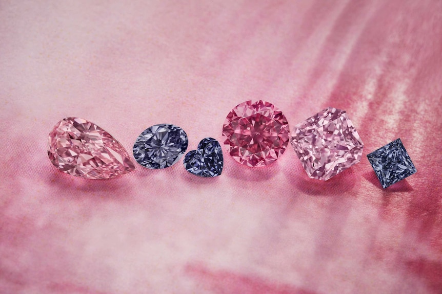 A close up of six pink, violet and red diamonds against a pink background