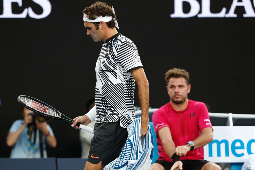 Roger Federer walks past Swiss compatriot Stan Wawrinka during a change of ends