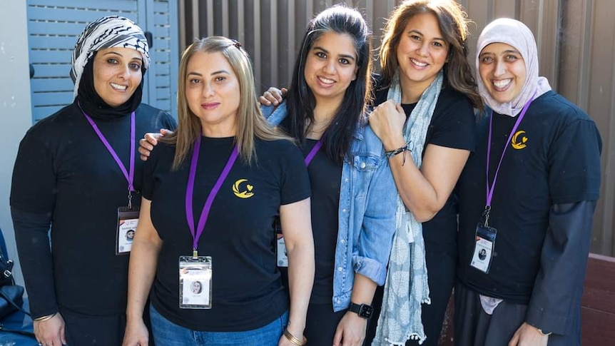 Five women, some wearing headscarves, who volunteer for the community care kitchen.