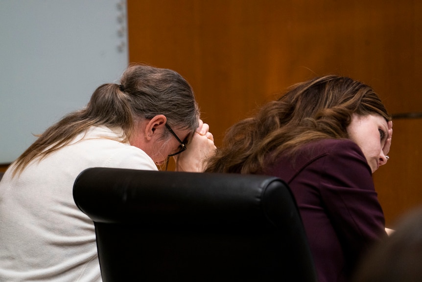 Jennifer Crumbley, izquierda, llora mientras su abogada Shannon Smith le sostiene la cabeza entre las manos.