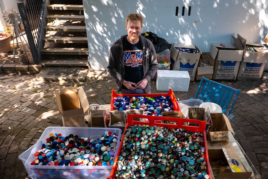 Tim Miller stands behind a table full of different lids.