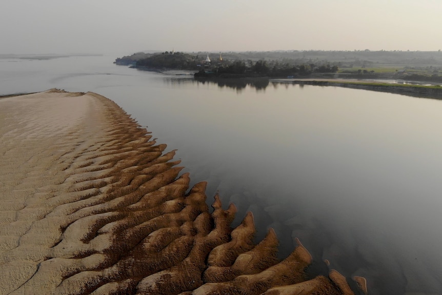 A rippled sand bank disappearing into the still Ayeyarwady River