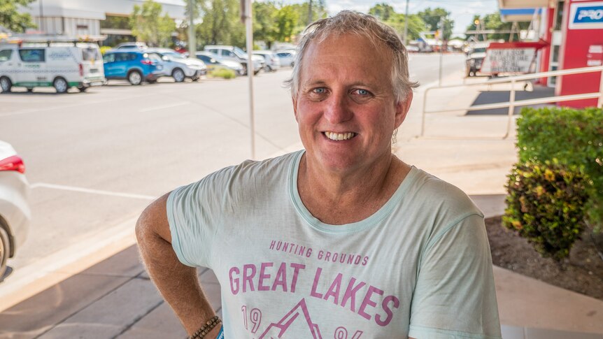 A man with grey hair wearing a t-shirt standing in a Mount Isa street.