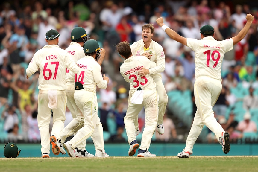 Marnus Labuschagne hugs a screaming Steve Smith as other Australian cricketers run to them.