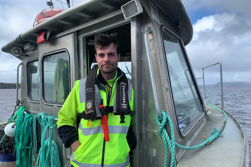 Petuna worker Tom Mountney stands on a boat in Macquarie Harbour