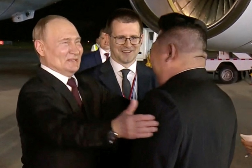 Vladimir Putin smiling, with his hand on Kim Jong Un's shoulder. 