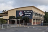 The empty playground and school buildings labelled with Heathdale Christian College, under an overcast morning sky.