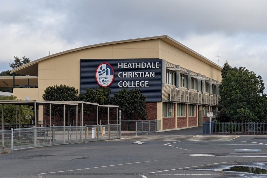 The empty playground and school buildings labelled with Heathdale Christian College, under an overcast morning sky.