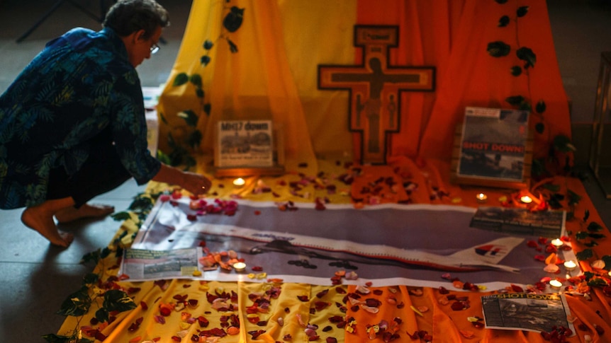 A woman lighting a candle at memorial for MH17 passengers