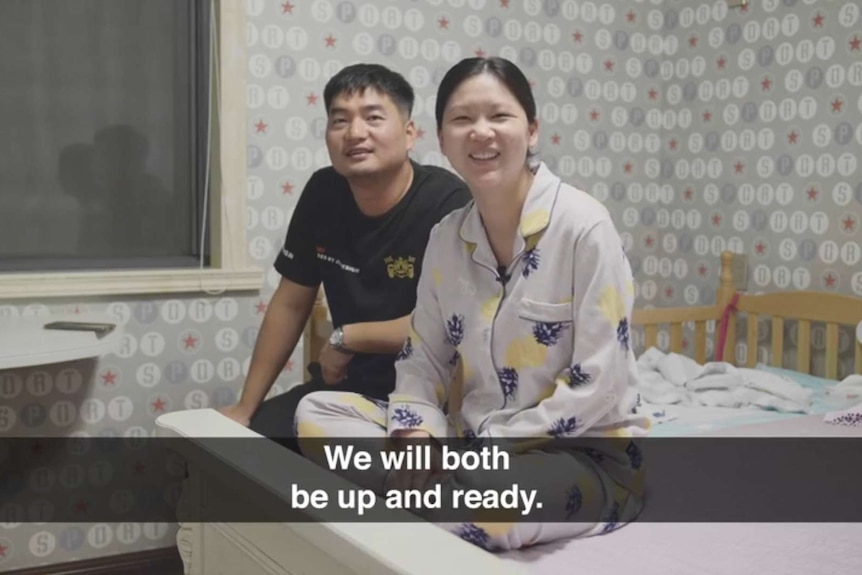A couple sits on a bed. Subtitle reads "we will both be up and ready".