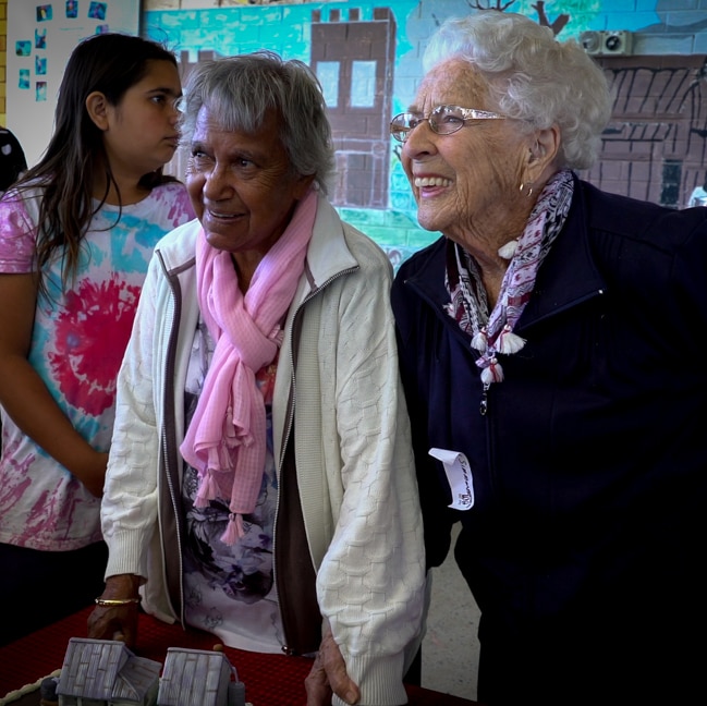 Two elderly woman smiling, one a Wahlabul/Bundjalung elder and one non-Indigenous