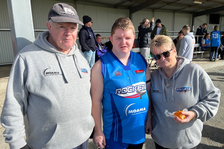 Tyler Wilson wearing a blue Rockets jersey, standing between his parents Gary and Elaine.