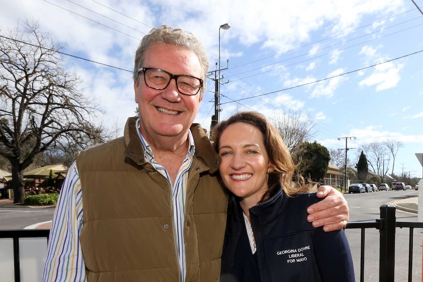 Alexander Downer smiling on the left with daughter Georgina standing to his right with his arm around her.