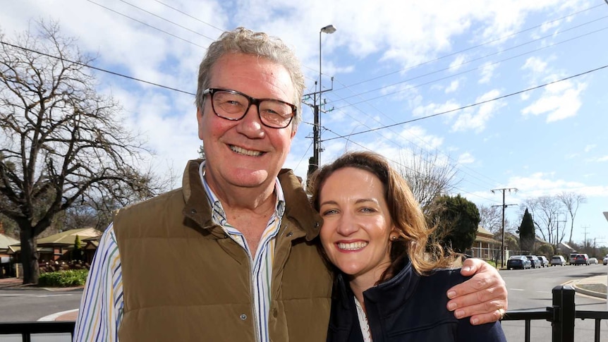 Alexander Downer smiling on the left with daughter Georgina standing to his right with his arm around her.