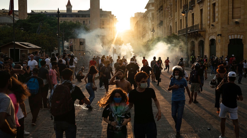 Demonstrators run from tear gas fired by police near the parliament building during a protest against the political elite.