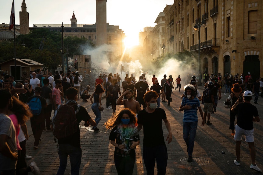 Demonstrators run from tear gas fired by police near the parliament building during a protest against the political elite.