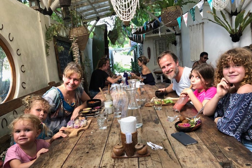 A man and woman sit at a restaurant table with four small children 